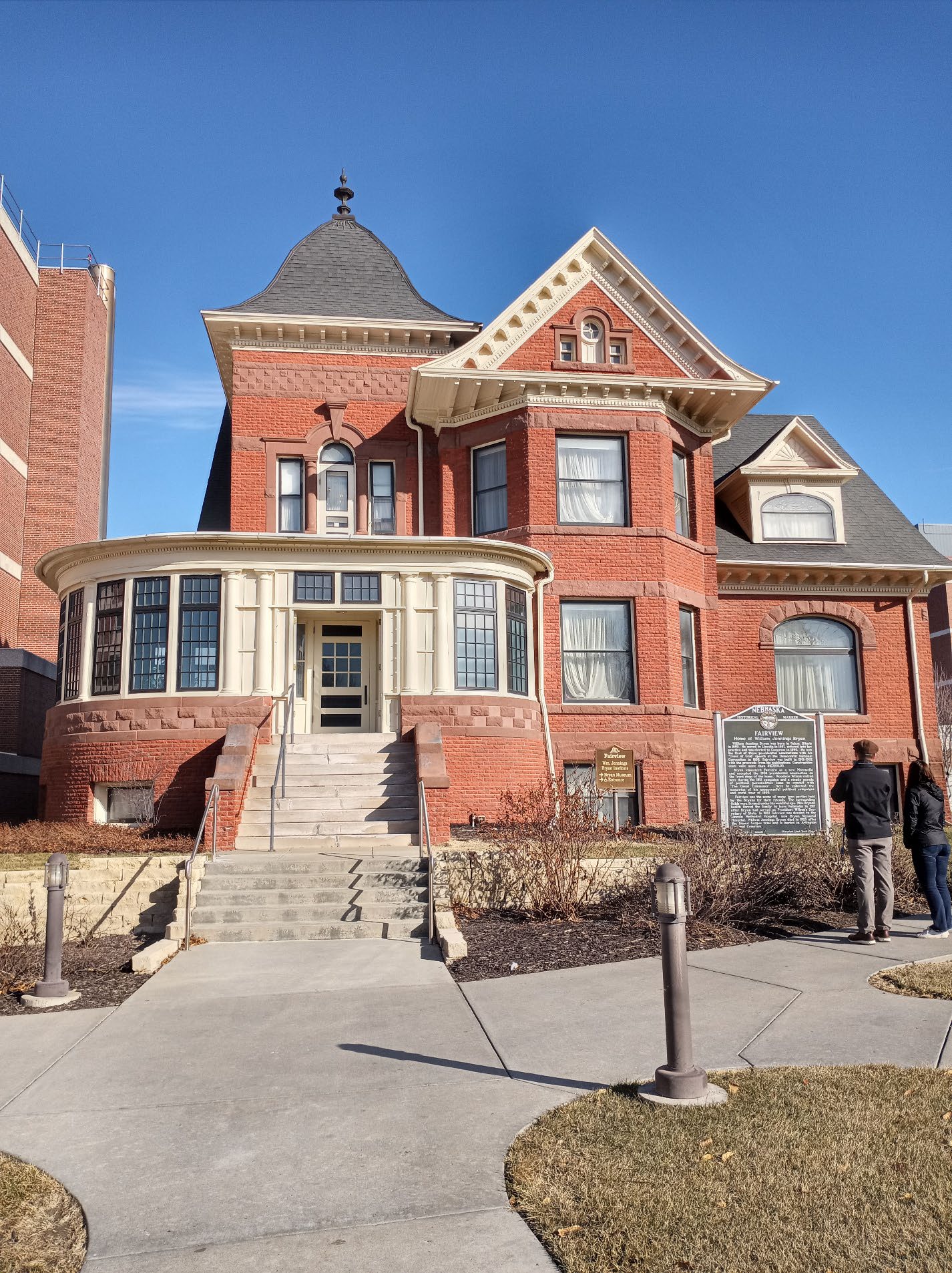 A full view of the Fairview Mansion at the front of the home. Two people stand by a historical marker.